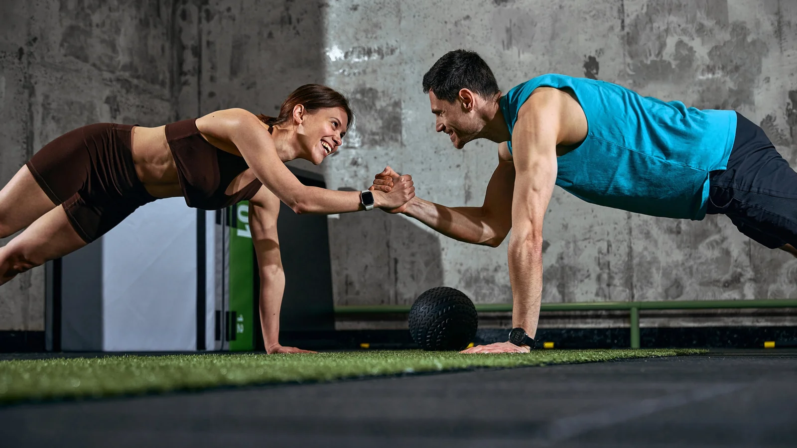 Personal Training: zwei Trainierende beim High Five in der Liegestützposition