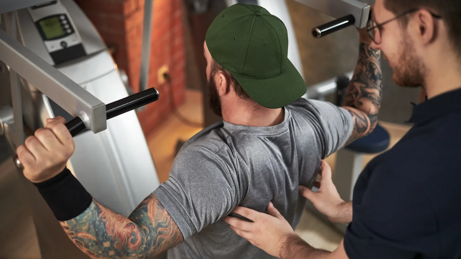 Trainer mit Sportler am Kraftgerät